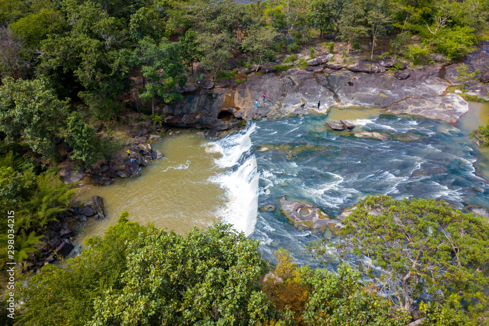 Obraz premium Drone shot, top view, of a stream with some small waterfalls, on a stony surface, surrounded by trees, on a sunny day,Tadton Waterfall,Ubonratchathani Porvince, North Eastern of Thailand,ASIA.
