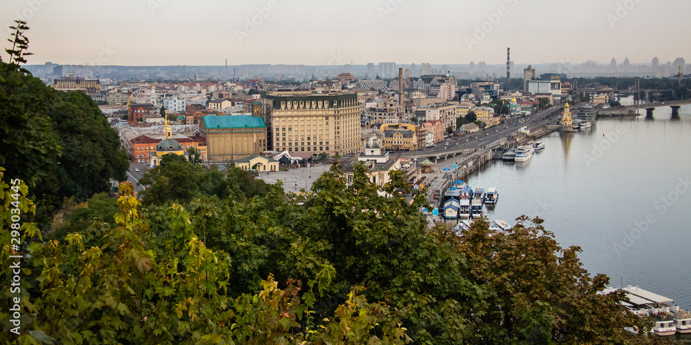 Fototapeta premium Tour of Kiev in the center of Europe. View of the Dnieper, Trukhanov island and a foot bridge. Park fountain and sunset on the horizon..