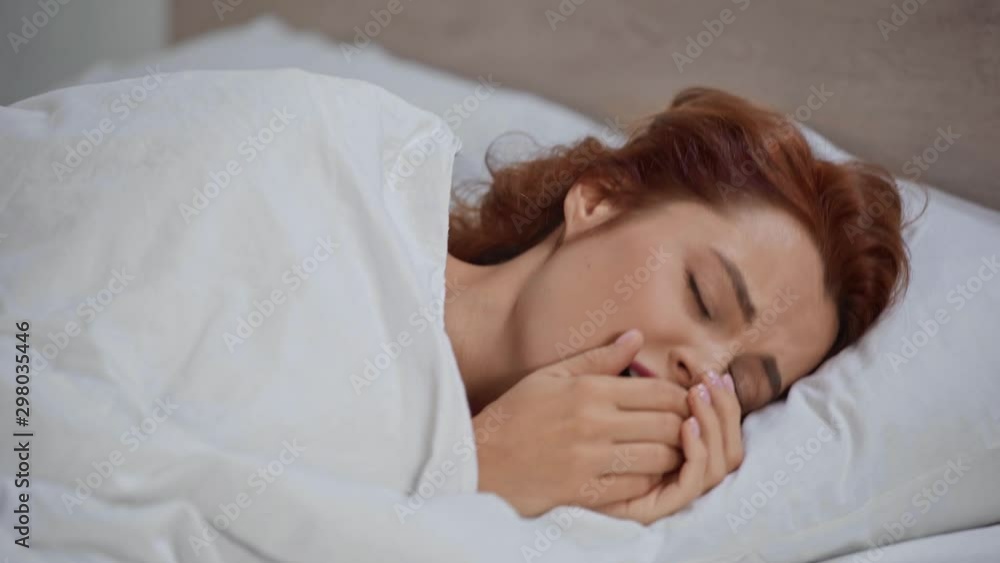 sick woman coughing while lying in bed under blanket sick woman coughing while lying in bed under blanket