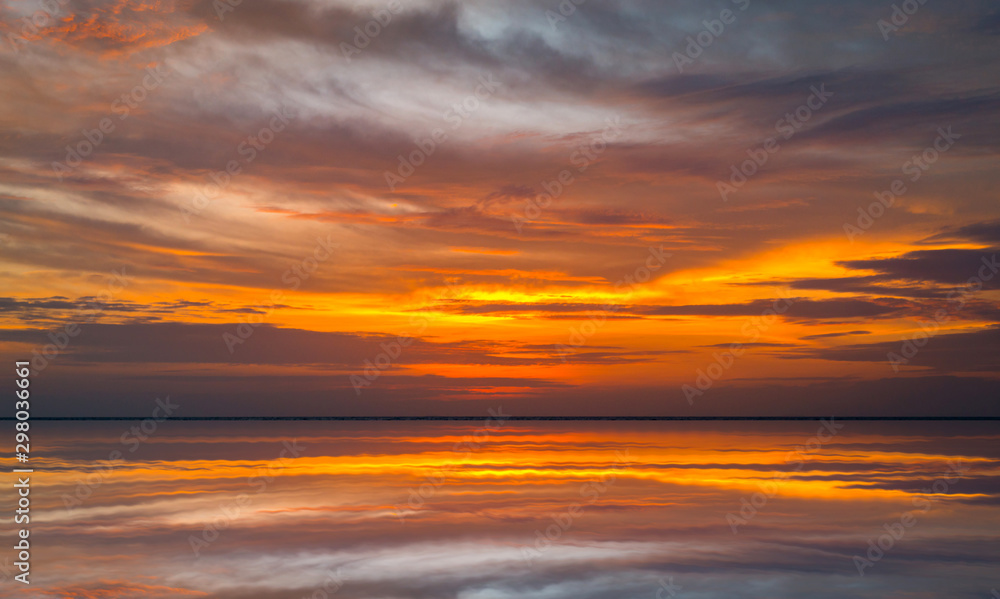 Panorama Reflection of vivid sunset sky over sea.Colorful sunrise with Clouds over ocean.Sky reflection on water.