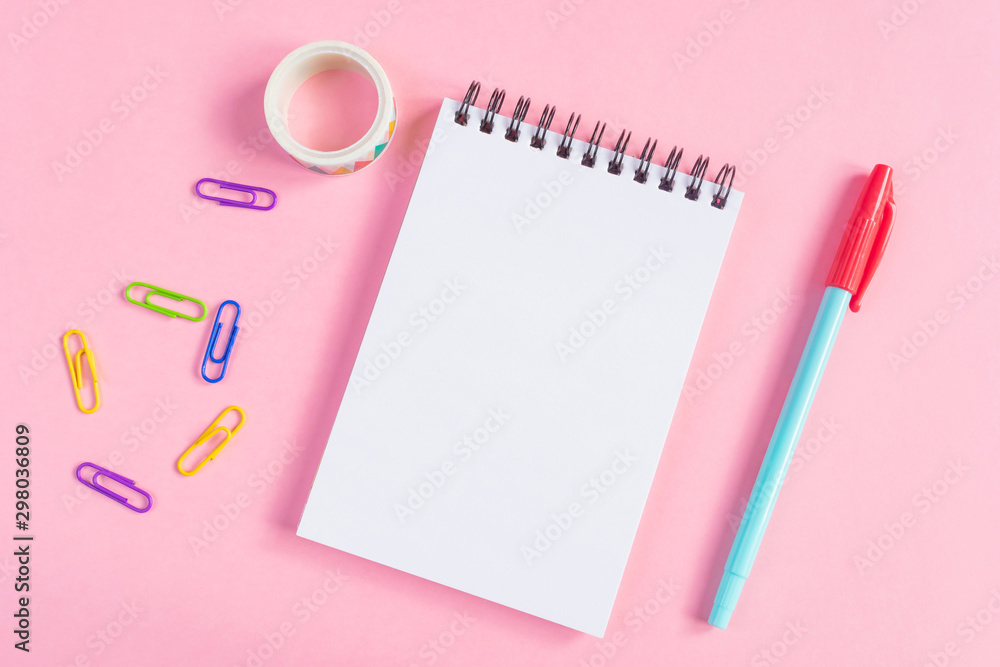 Pen, paper clips, notebook on a pink background. Place for text, minimalism. School, office, education concept. Pen, paper clips, notebook on a pink background. Place for text, minimalism. School, office, education concept.
