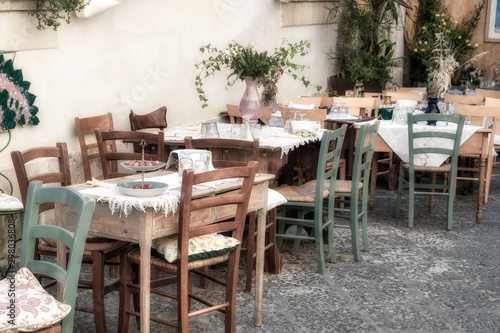 View of a restaurant outdoors tables, in the city centre of Ortigia (Italy, Sicily, Siracusa), UNESCO World Heritage Site.