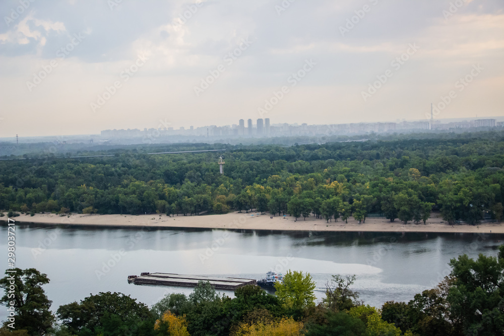 Fototapeta premium Tour of Kiev in the center of Europe. View of the Dnieper, Trukhanov island and a foot bridge. Park fountain and sunset on the horizon..