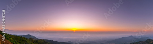 Panorama Sunlight with dramatic sky. Cumulus sunset clouds with sun setting down over mountain on dark background.Vivid orange cloud sky.