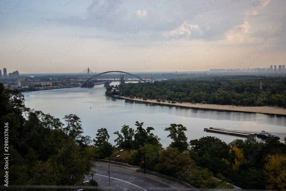 Tour of Kiev in the center of Europe. View of the Dnieper, Trukhanov island and a foot bridge. Park fountain and sunset on the horizon..