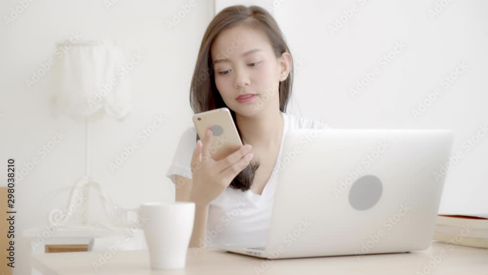 Beautiful young freelance asian woman smiling working on laptop computer and talking mobile smart phone at desk office with professional, girl using notebook, business and lifestyle concept. Beautiful young freelance asian woman smiling working on laptop computer and talking mobile smart phone at desk office with professional, girl using notebook, business and lifestyle concept.