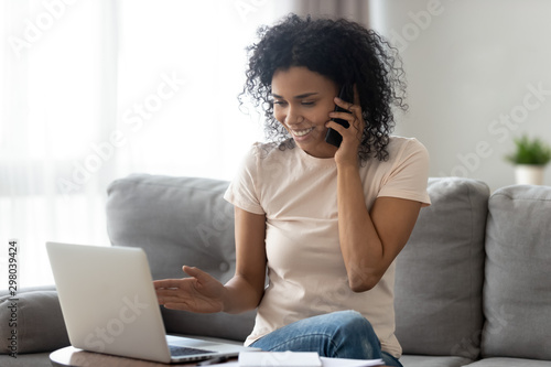 Smiling black woman multitask at home using gadgets