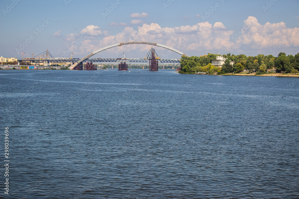 Naklejka premium Tour of Kiev in the center of Europe. View of the Dnieper, Trukhanov island and a foot bridge. Park fountain and sunset on the horizon..
