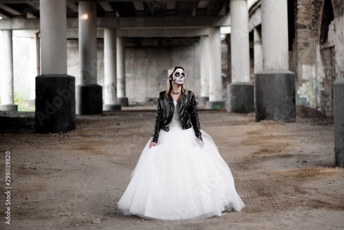 Portrait of zombie woman with painted skull face under a bridge.
