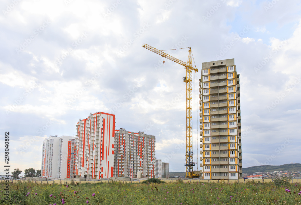 Fototapeta premium high-rise building construction. Construction crane against the sky. City under construction in the mountains