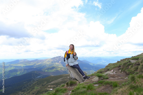 Young happy female tourist wearing yellow jacket standing in Alps mountains. photo