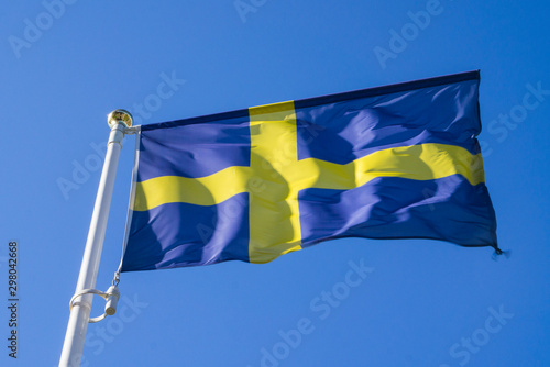 Swedish flag waving in the wind against a blue sky.