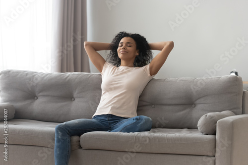 Happy black girl relaxing on comfortable couch at home