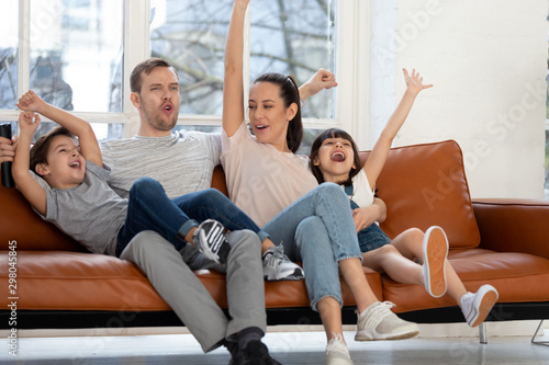 Cuadro en lienzo Overjoyed family of four watching football basketball match on tv