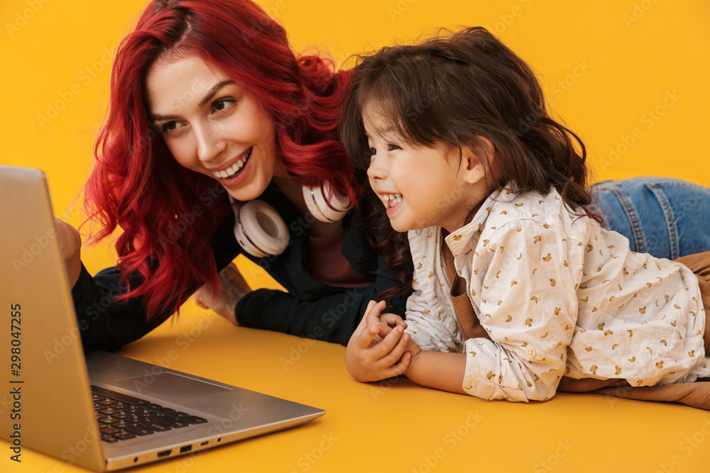 Image of smiling woman and her daughter looking at screen of laptop Image of smiling woman and her daughter looking at screen of laptop