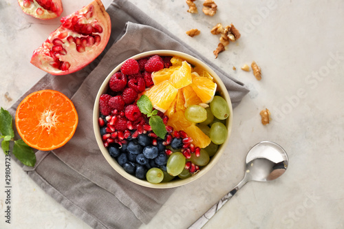Фотография Bowl with tasty fruit salad on light background