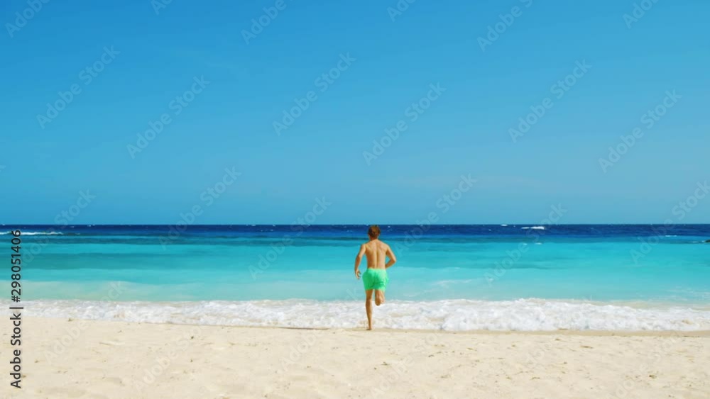 Tanned young male running and diving into sea Tanned young male running and diving into sea
