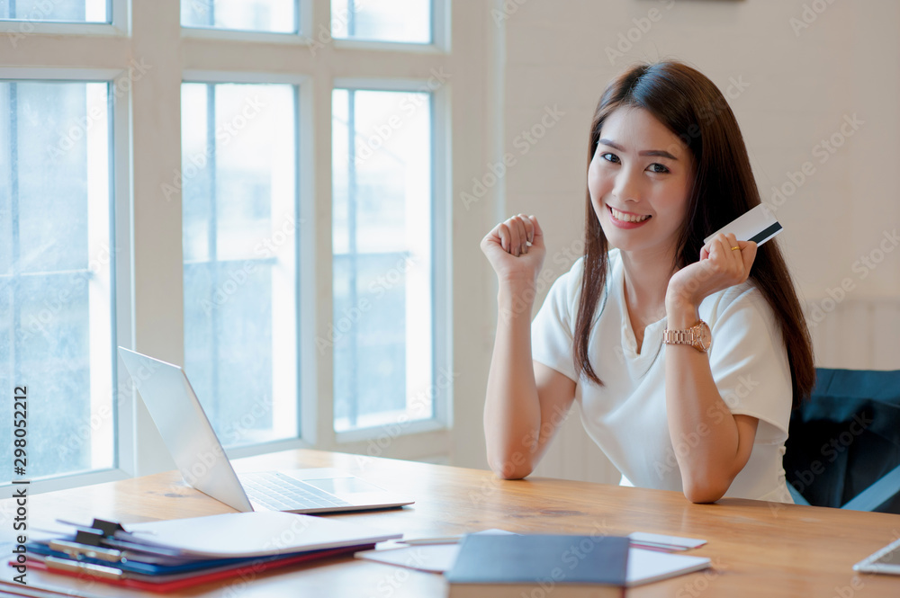 Asian women are shopping online using a credit card. happily Asian women are shopping online using a credit card. happily