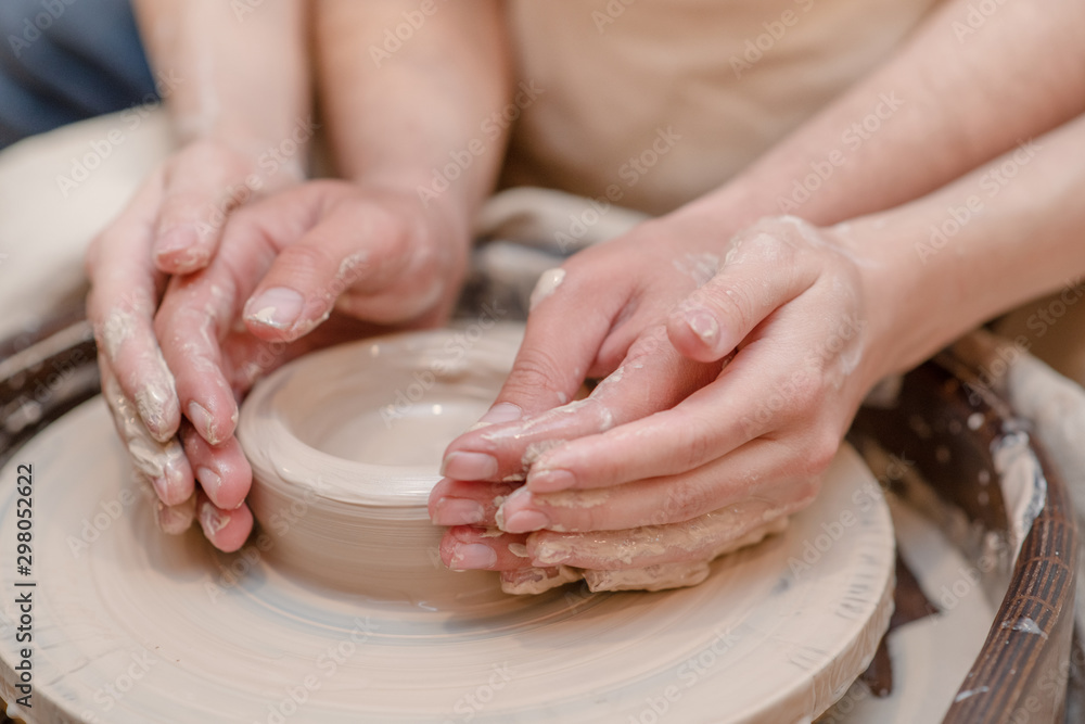Potter teaches woman to make ceramic pot on the pottery wheel Potter teaches woman to make ceramic pot on the pottery wheel