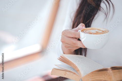 A beautiful woman wearing a long-sleeved white shirt sitting at a coffee shop.