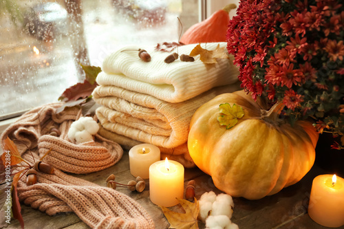 Beautiful autumn composition with pumpkin  warm clothes and candles on window sill