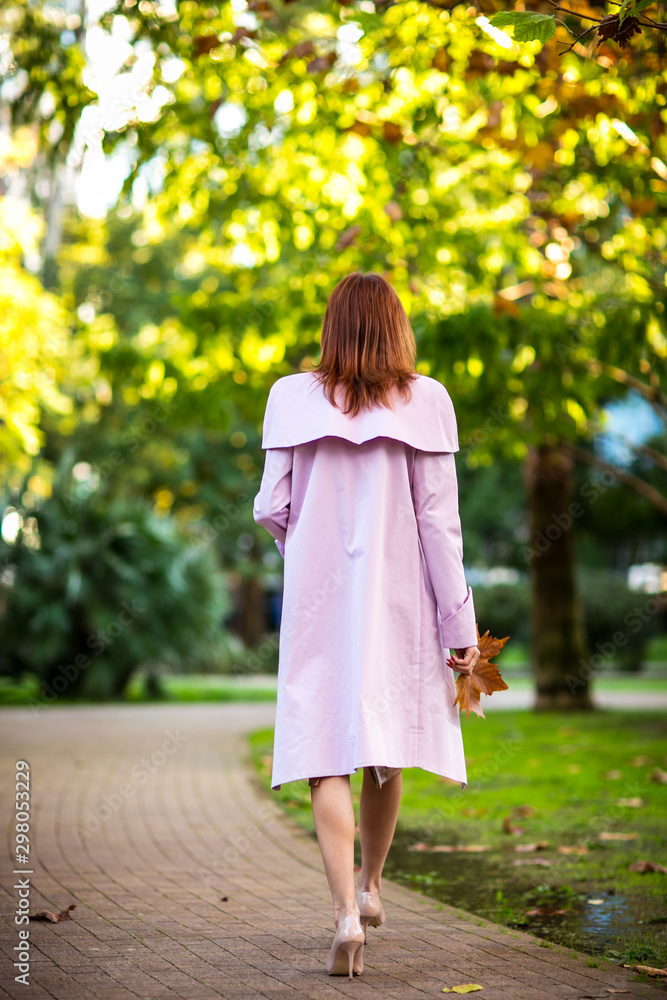 the girl is brown-haired, walks in the Park in the autumn, in a leather, stylish skirt,and a pink autumn cloak, with a leaf in her hand the girl is brown-haired, walks in the Park in the autumn, in a leather, stylish skirt,and a pink autumn cloak, with a leaf in her hand