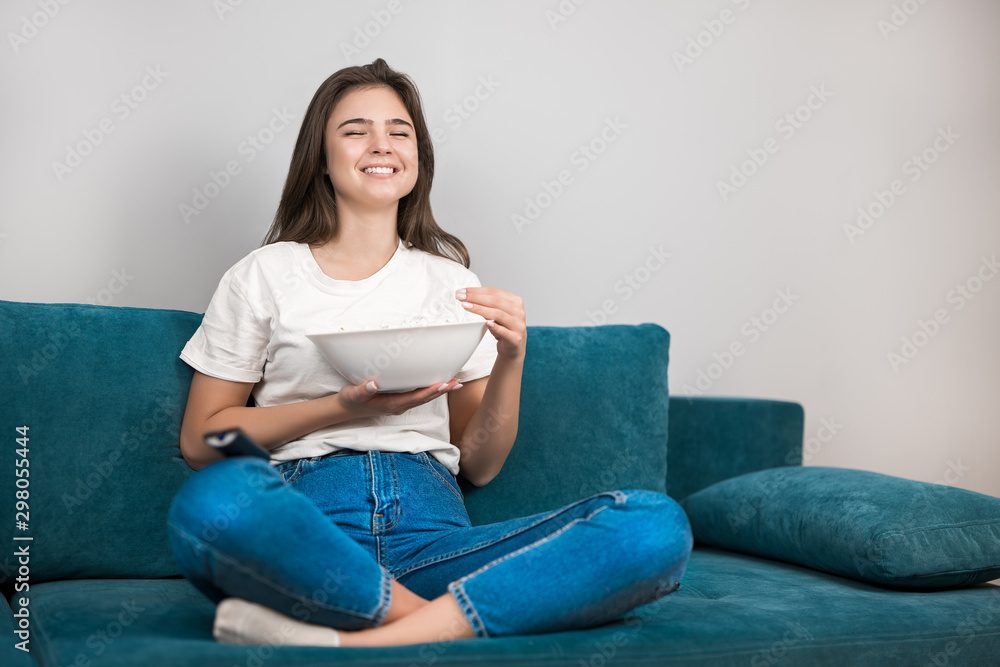 beautiful young woman watching funny movie on the sofa eating popcorn feeling comfortable on the sofa at home laughing beautiful young woman watching funny movie on the sofa eating popcorn feeling comfortable on the sofa at home laughing
