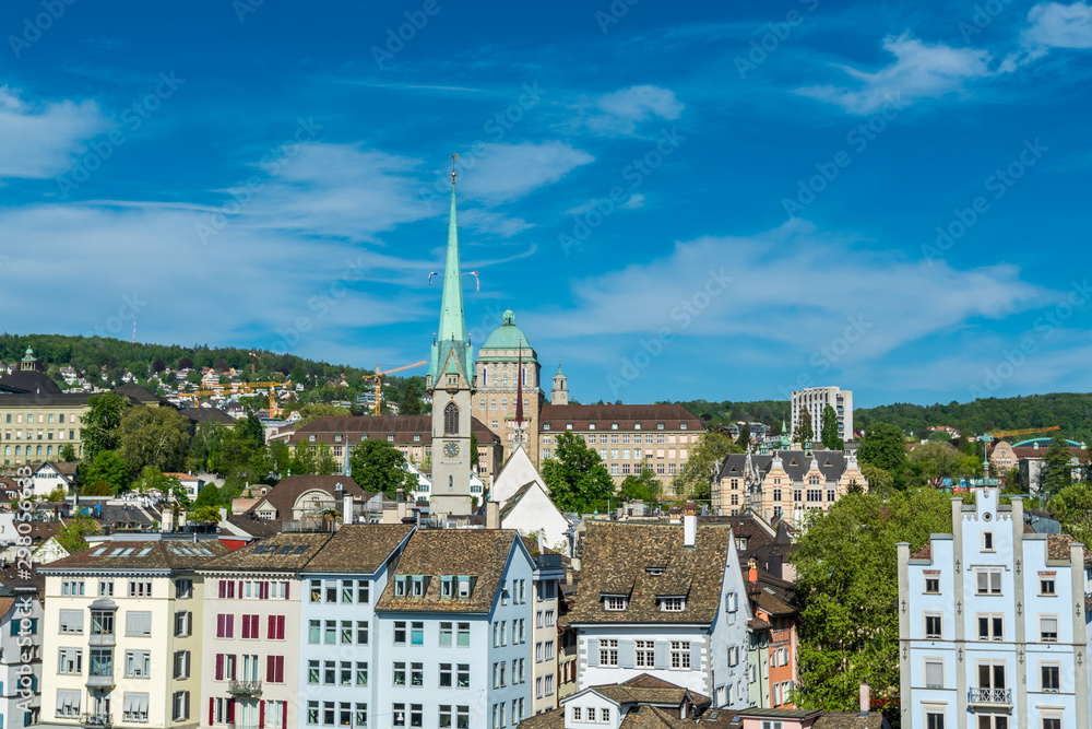 View of the historic center of Zurich at the bank of Limmat River, with beautiful house rooftops and University Zurich and church of Predigerkirche, view form Lindenhof hill.