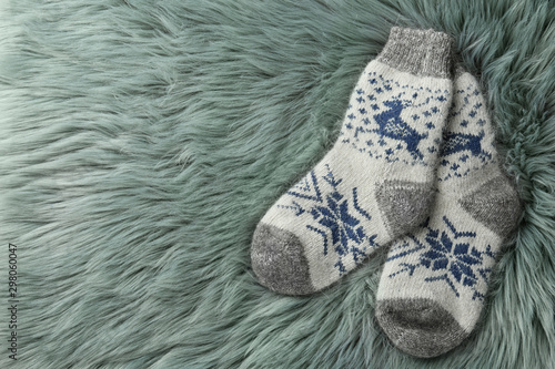 Knitted socks on grey faux fur, flat lay. Space for text © New Africa