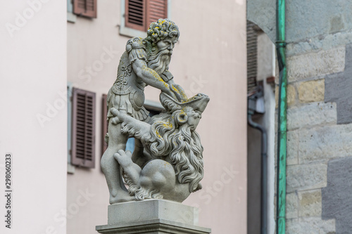Samson statue in front of a beautiful facade of a building. Street view of Old city of Zurich with a fountain in Switzerland