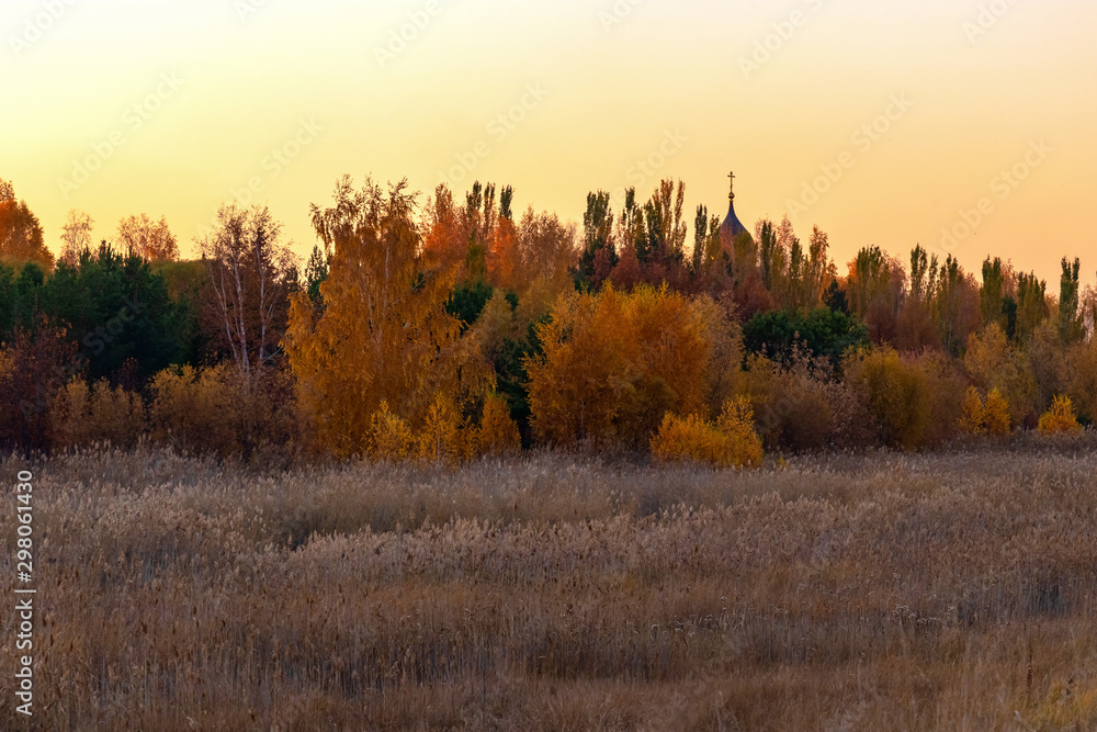 Beautiful rural landscape / autumn colorful park and church dome against the evening sunset