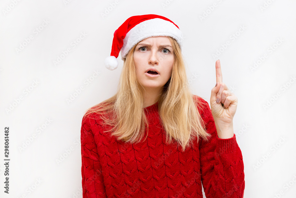 Thinking and reflecting girl in a Christmas hat. Emotional woman in red santa claus hat. Holiday concept. Emotion facial expression. Thinking and reflecting girl in a Christmas hat. Emotional woman in red santa claus hat. Holiday concept. Emotion facial expression.
