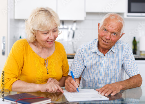 Mature family couple sitting at table with documents together