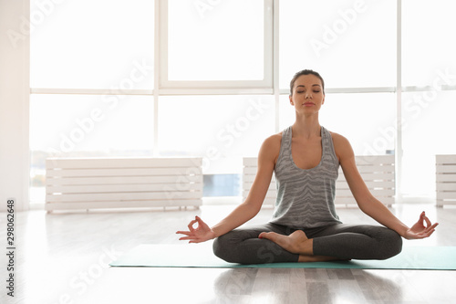 Young woman practicing yoga in studio. Accomplished pose (Siddhasana) photo
