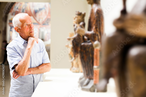 Mature man visiting sculptures exhibition