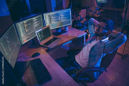 Portrait of his he nice attractive skilled expert guy monitoring remotely many projects online internet intranet blockchain start-up hardworking at dark room workplace station indoors