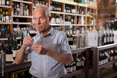 Elderly man inspecting quality of red wine