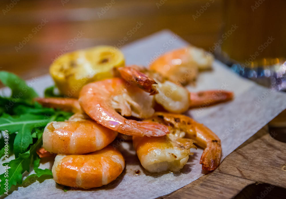 fried roasted shrimps with lemon and arugula on wooden table fried roasted shrimps with lemon and arugula on wooden table