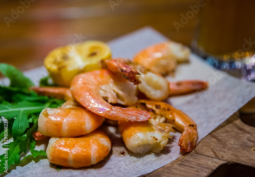 fried roasted shrimps with lemon and arugula on wooden table
