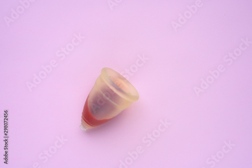 menstrual cup with blood on pink background. space for text