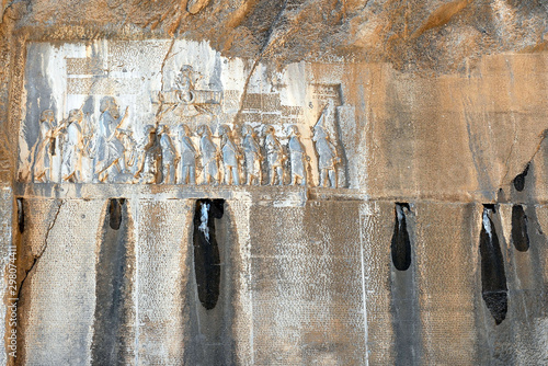 Behistun Inscription and large rock relief on a cliff at Mount Behistun in Kermanshah Province of Iran. This multilingual inscription was crucial to the decipherment of cuneiform script. photo