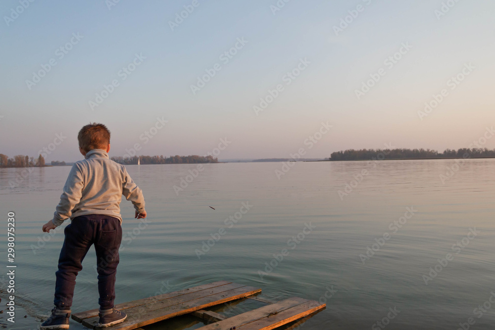 Little boy child throws plants into the water