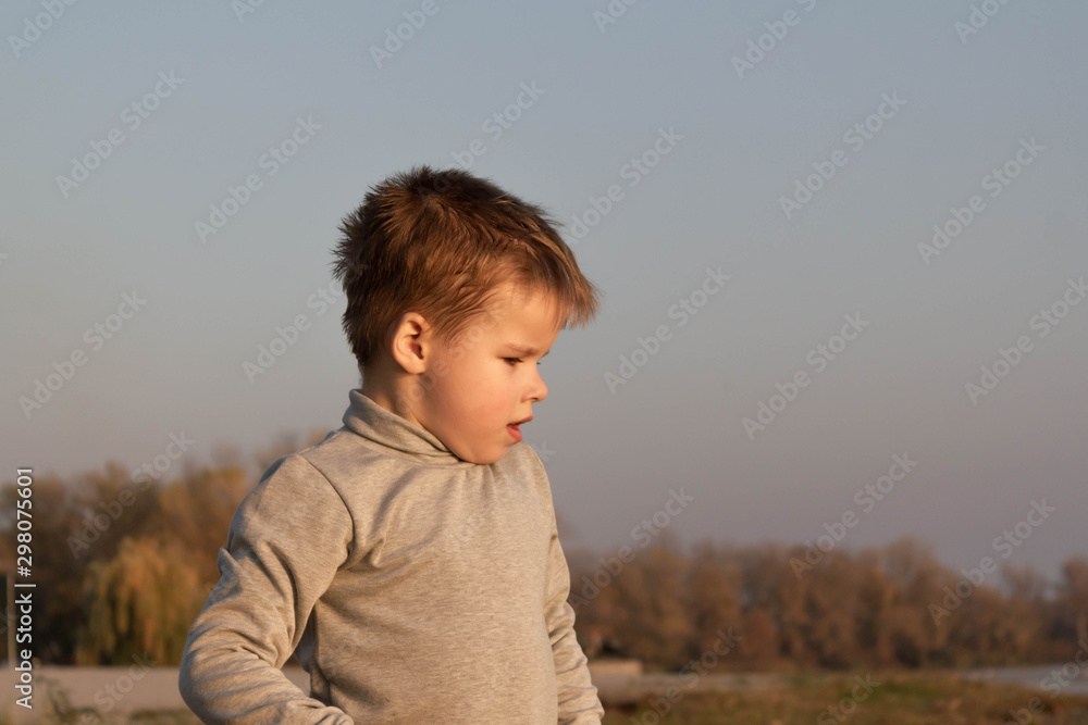 Little kid boy dreaming, pensive, on the beach near the water Little kid boy dreaming, pensive, on the beach near the water