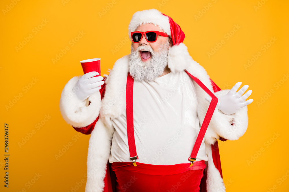 Funky big belly christmas grandfather in red x-mas hat headwear visit noel party hold disposable glass cup mug with beer feel crazy isolated over yellow color background - obrazy, fototapety, plakaty 