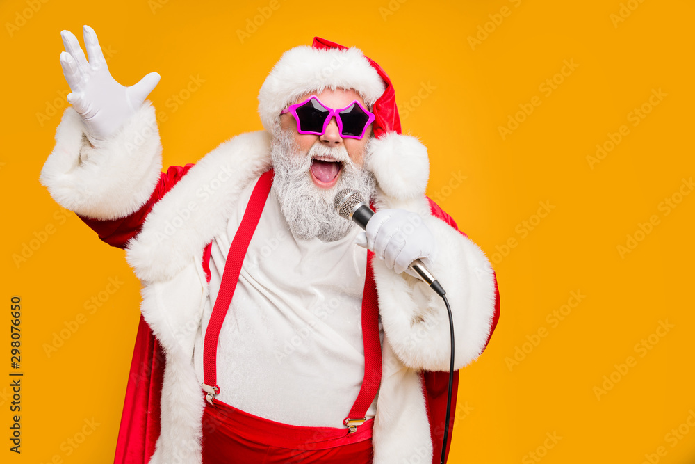 Portrait of fat big belly crazy funky santa claus hold microphones have live x-mas performance sing carols on christmas night wear red hat headwear trendy suspenders isolated yellow color background - obrazy, fototapety, plakaty 