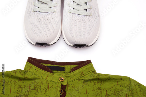 Gray men's sneakers and a folded green shirt on a white background. Things for sports.