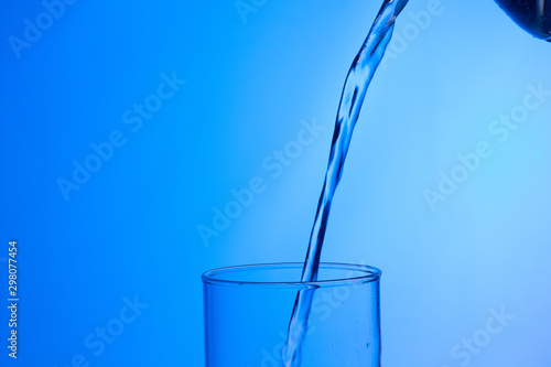 Agua entrando en un recipiente transparente de crital o plástico; agua salpicando 