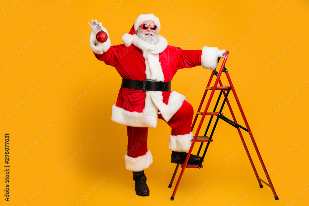 Full body photo of funny funky grey hair santa claus climb stairs want hang christmas tinsels decorate fir tree for x-mas celebration party isolated over bright color background Full body photo of funny funky grey hair santa claus climb stairs want hang christmas tinsels decorate fir tree for x-mas celebration party isolated over bright color background