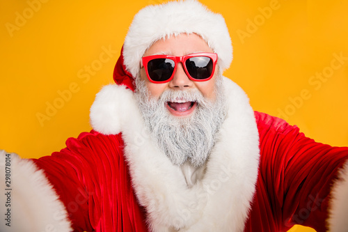 Funny funky santa claus blogger make selfie in blog post christmas eve congratulation video call greeting with holly x-mas noel celebration wear stylish spectacles isolated bright color background