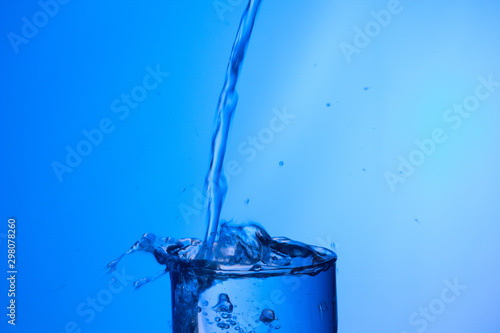 Agua entrando en un recipiente transparente de crital o plástico; agua salpicando 
